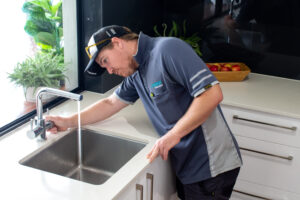 plumbing problems - a plumber repairing a tap with a water leak